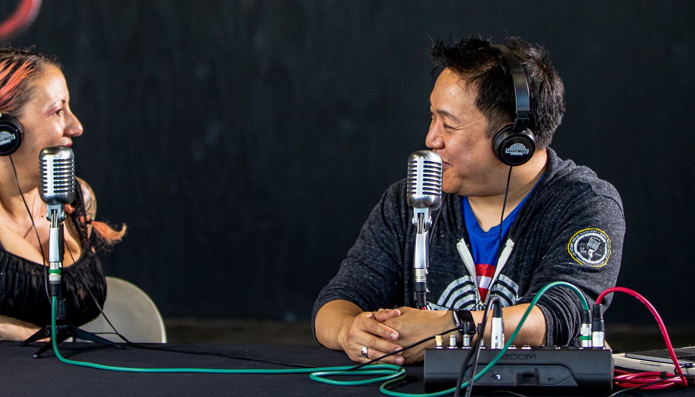 Two people headphones and L-8 Doing podcast