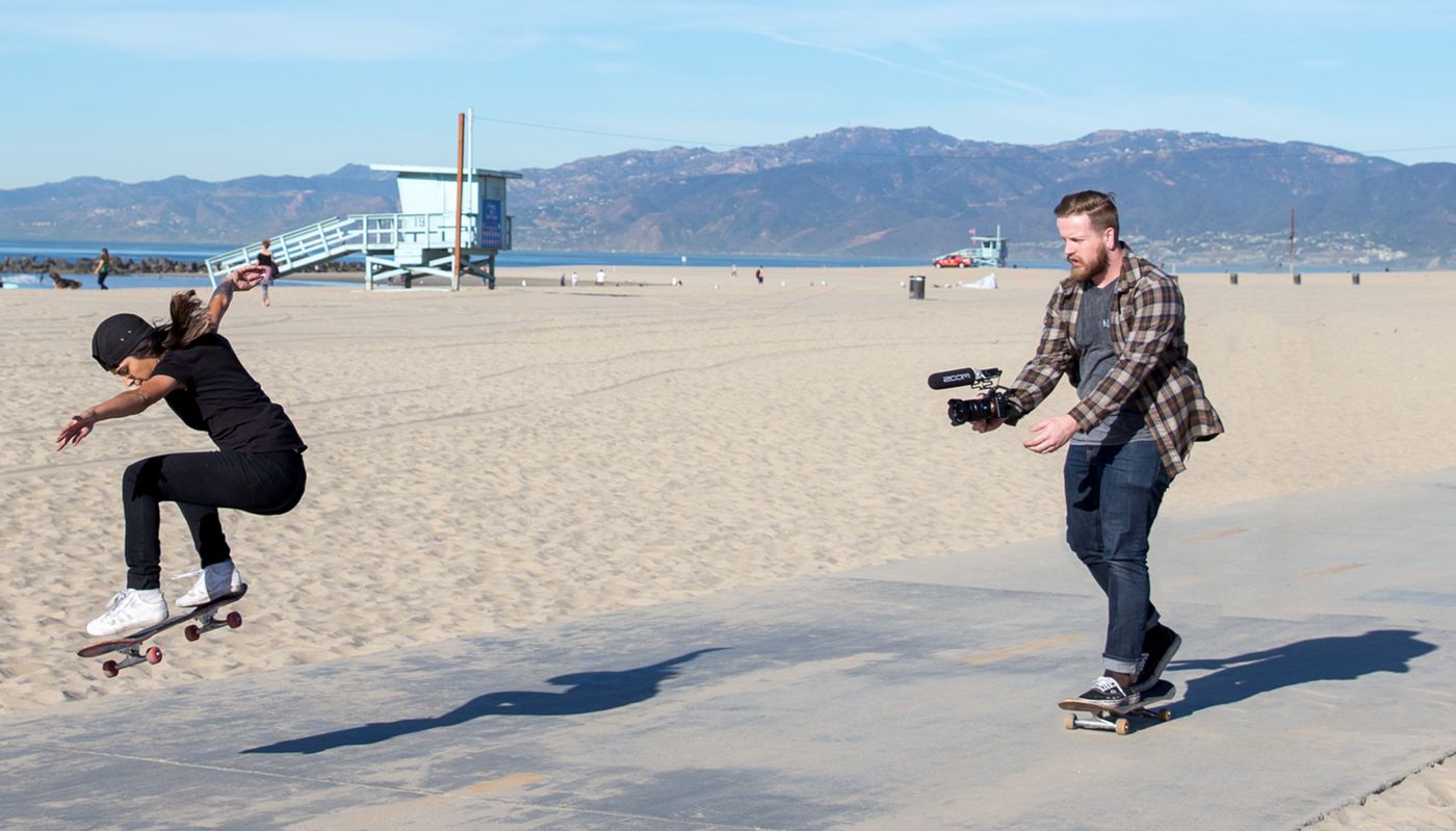 Videographer with F1-SP mounted to a DSLR on a skateboard, filming another skateboarder performing a trick