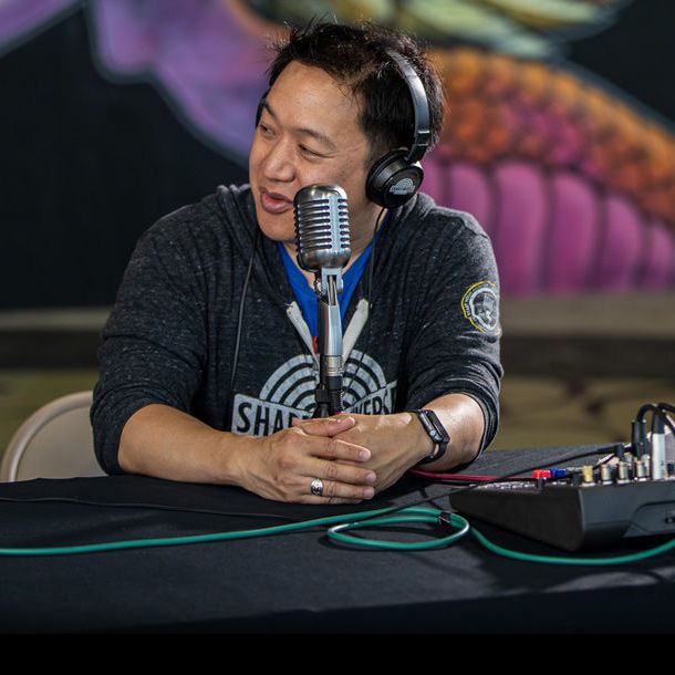 Ming Chen sitting with microphone recording a podcast