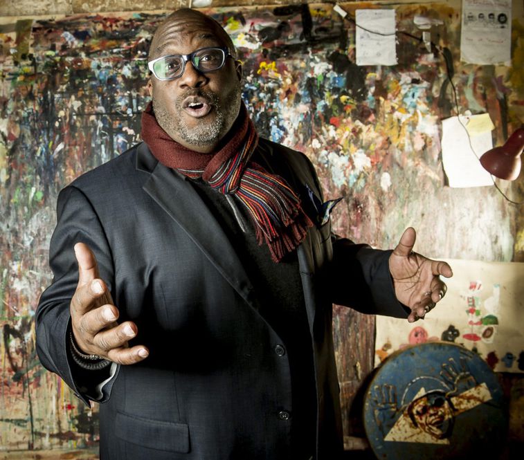 Carl Allen posing in front of wall with graffiti