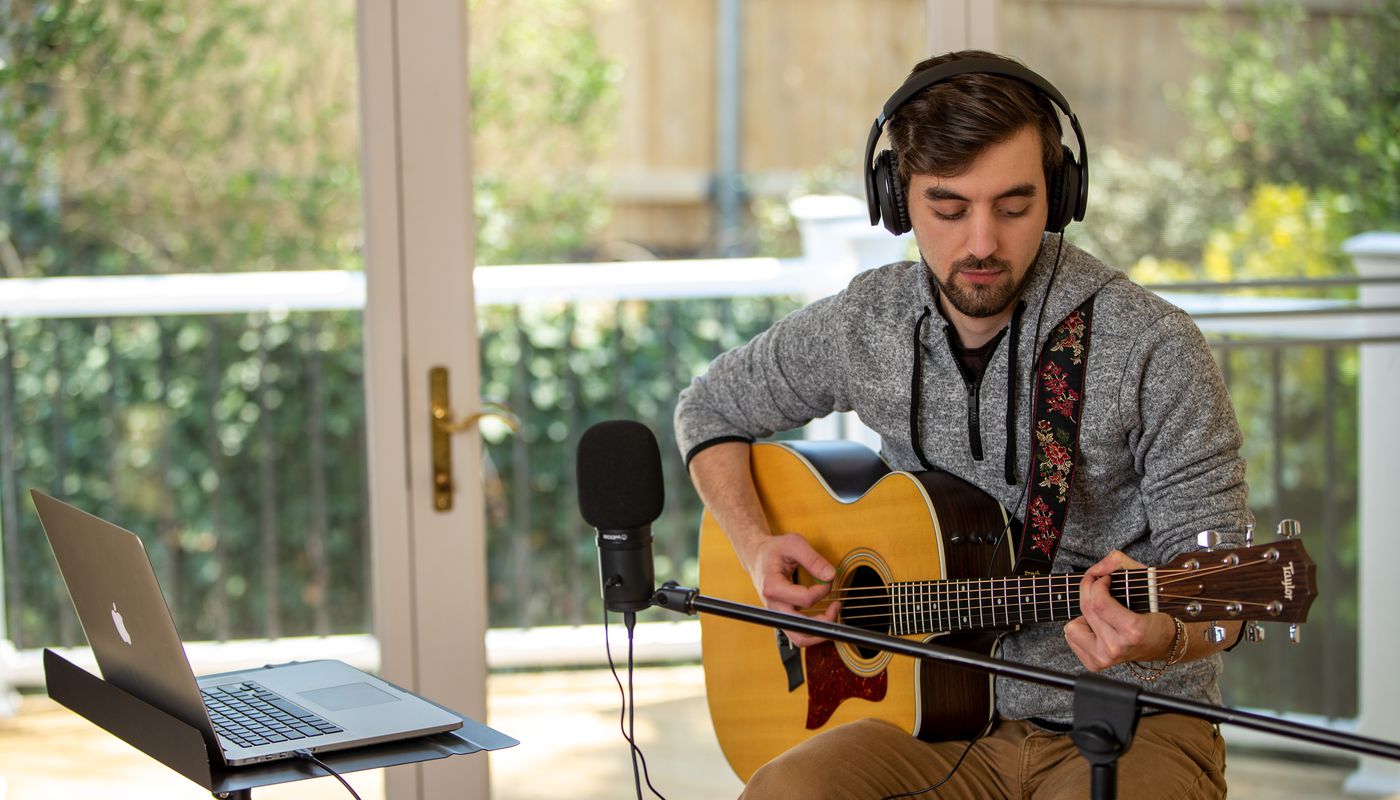 singer songwriter recording music onto his laptop using the ZUM-2 USB Microphone and monitoring his recording with headphones plugged into the mic’s headphone output.