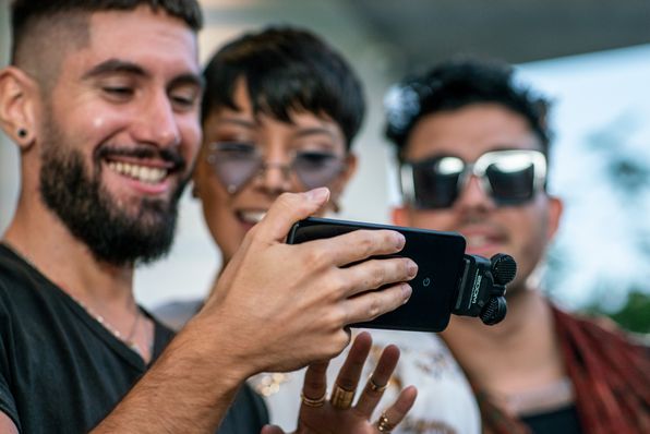Three musicians look into their smartphones to check the videos they have taken.