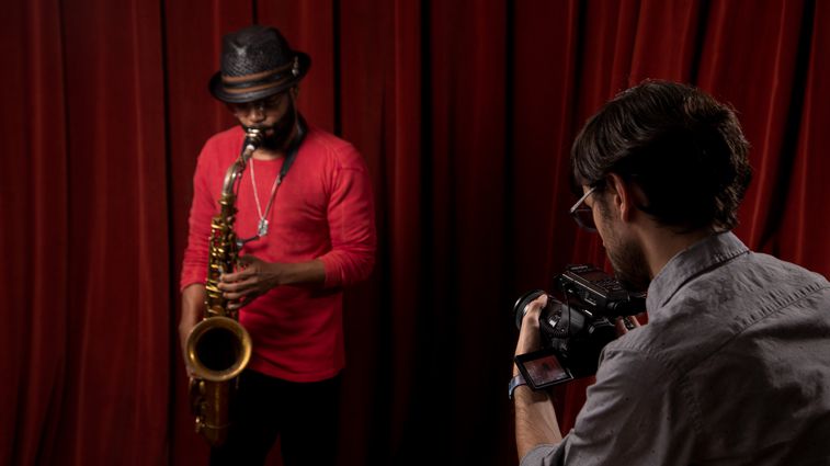 Saxaphonist Mark Shim plays while a videographer records him using a DSLR camera with an H4n Pro mounted to it, recording audio.