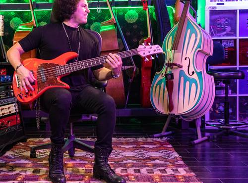 Carlitos del Puerto playing electric bass with his B6, with his upright bass nearby