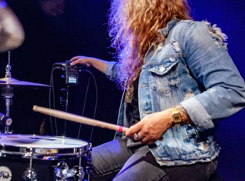 Drummer in the studio adjusting the gain knob on an H6, from behind the drum kit